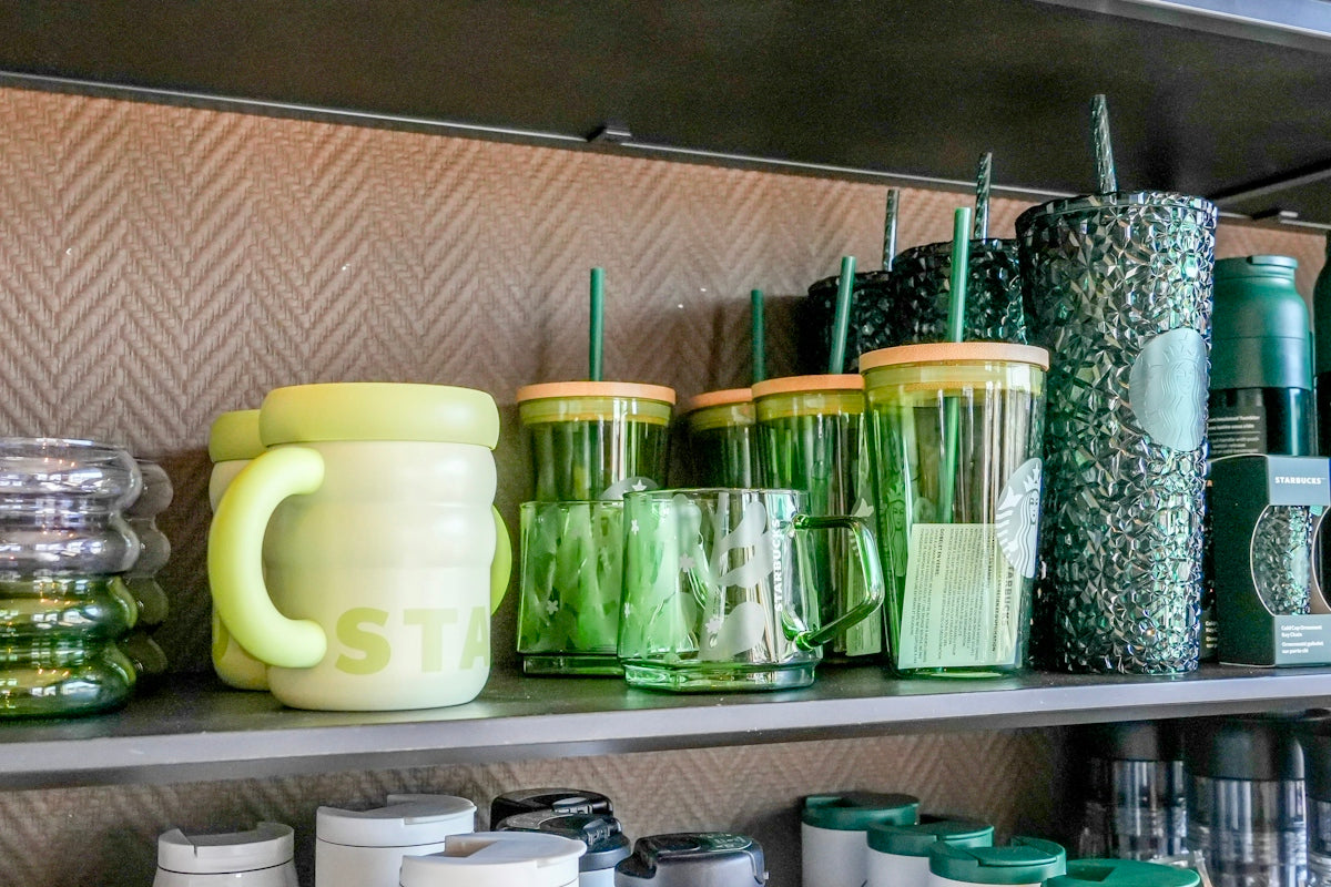 Green and yellow mugs and tumblers displayed on a shelf